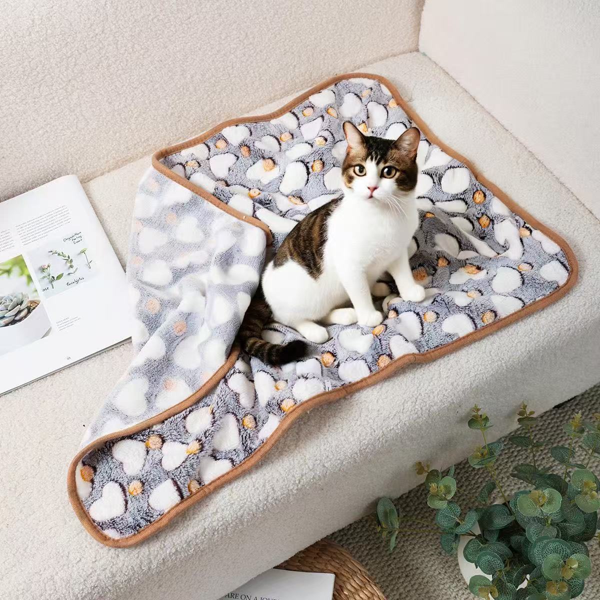 Cat sitting on a Blankora Snuggle Square gray fleece pet mat on a sofa